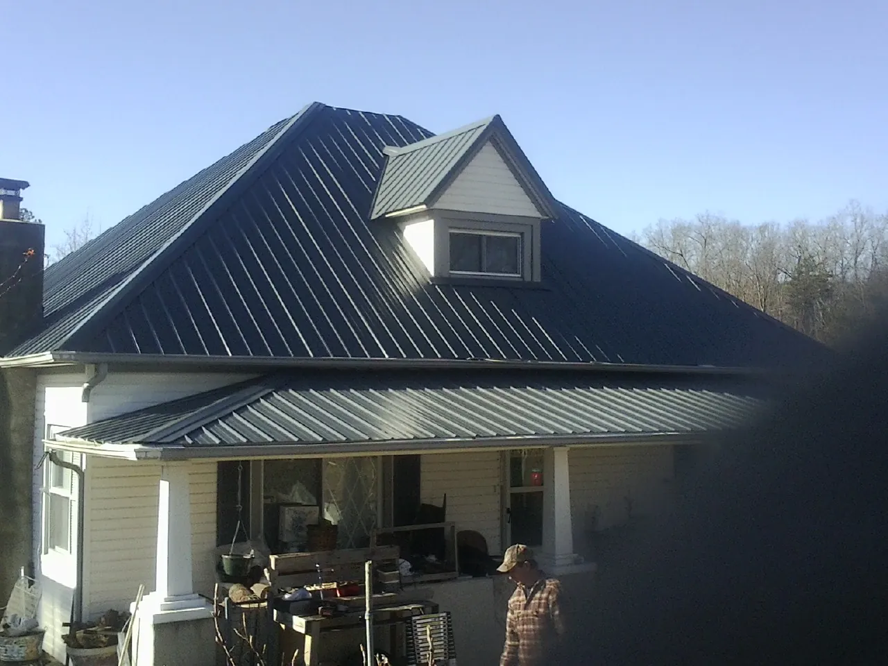 Dark blue standing seam metal roof with a dormer above a front porch in Buffalo